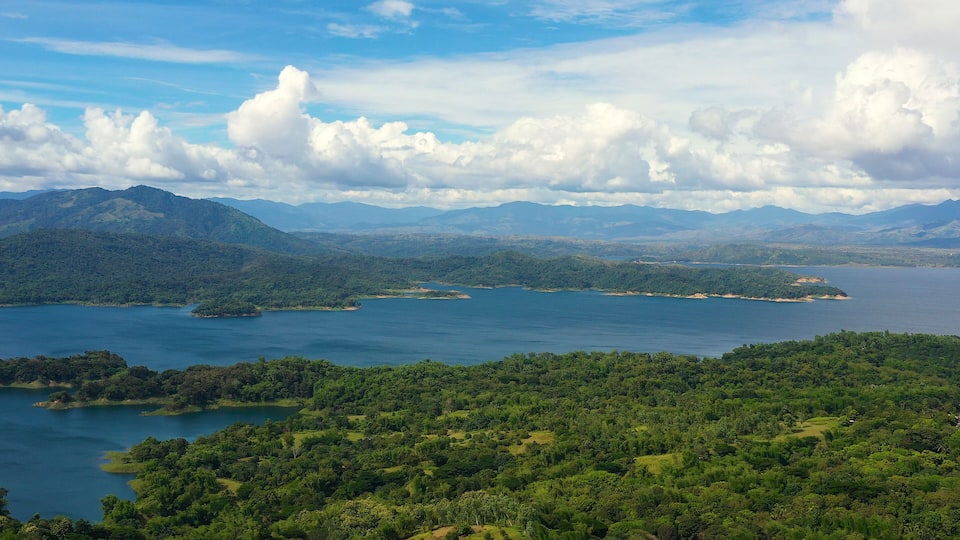 A coastal landscape with a large body of water surrounded by lush green hills and mountains.