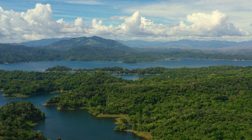 Clouds over a blue lake among green hills and mountains covered with rainforest. Aerial view: Pantabangan Lake. Philippines, Luzon.