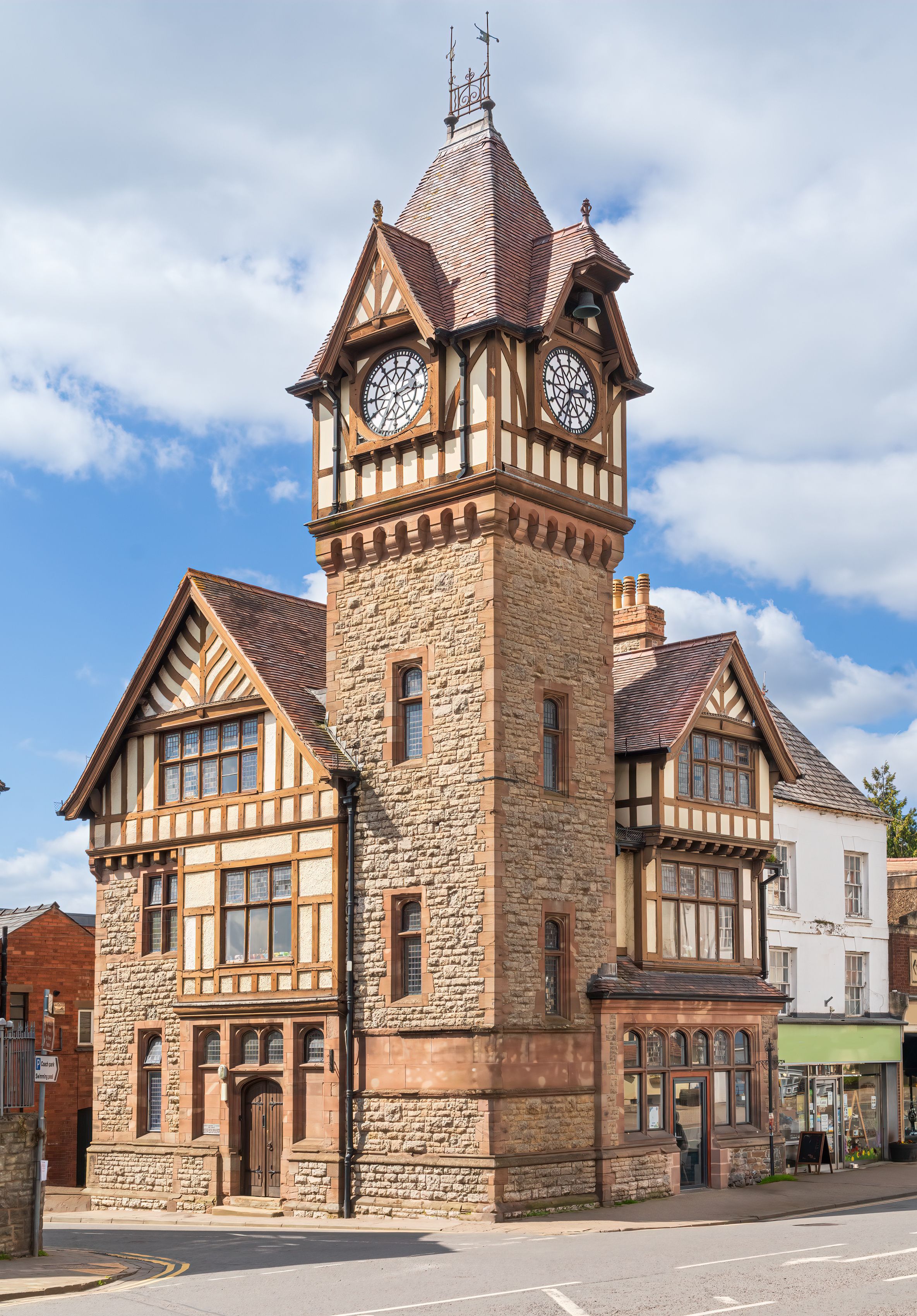 A historic building with a prominent clock tower, stone walls, and timber framing.