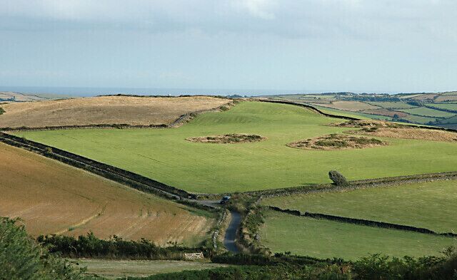 Rolling green fields, a narrow road, and distant hills.