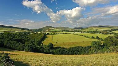 Rolling hills, green fields, and a partly cloudy sky.