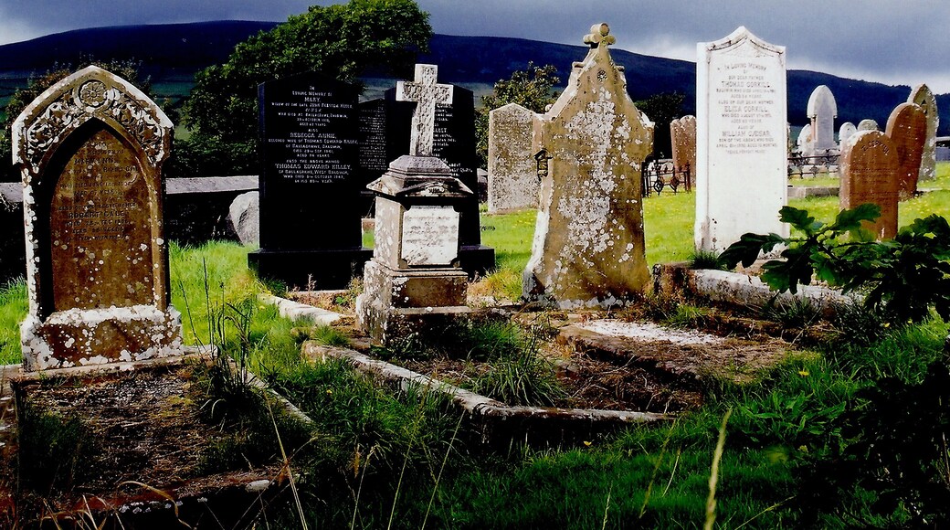 East Baldwin - St Luke's Church - Gravestones View is to the southwest from St Luke's Church graveyard towards B36. The lighting got my attention, as the gravestones were illuminated against the dark sky over the mountain in the background.
