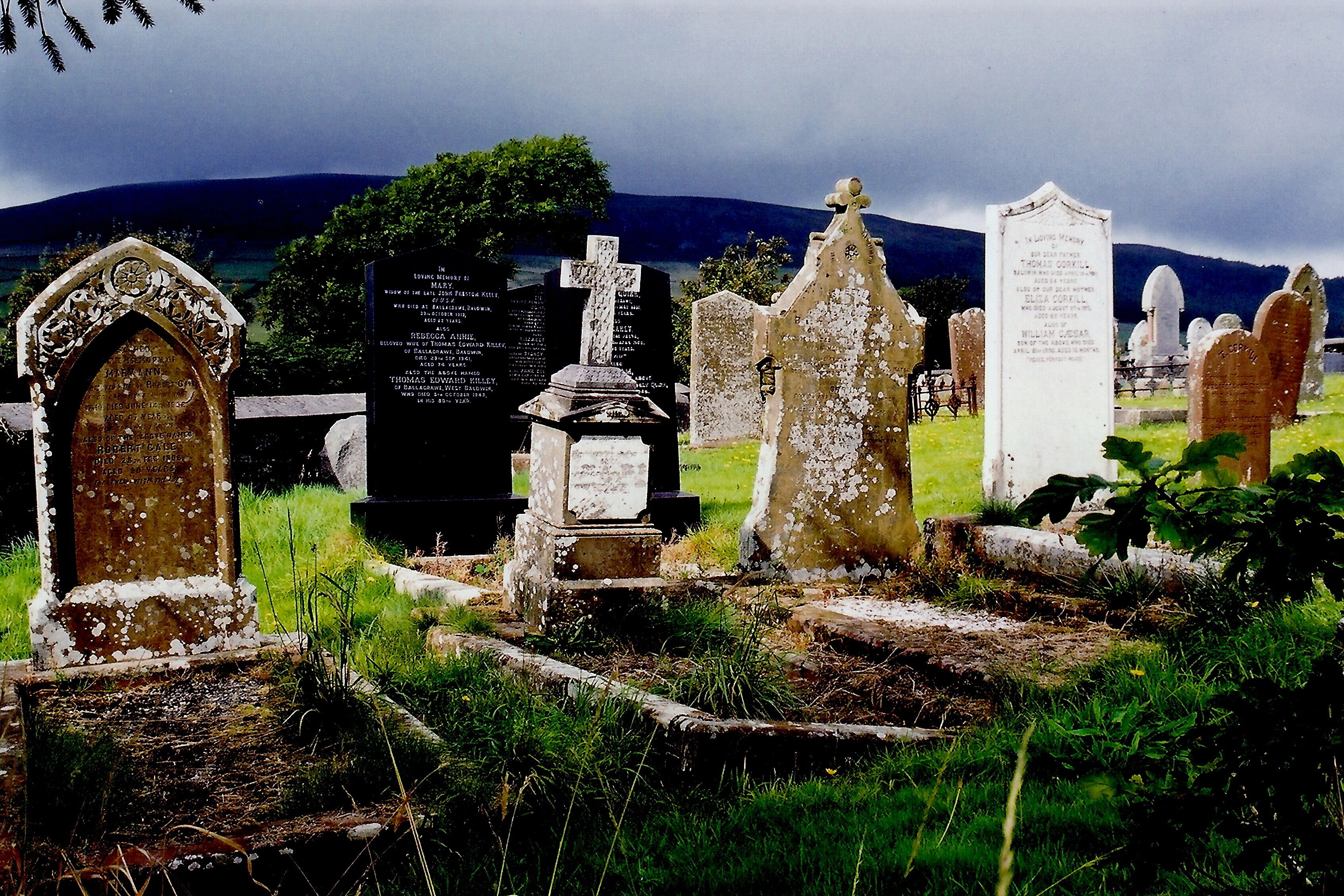 A cemetery with various gravestones and headstones, including a prominent cross and a memorial plaque.