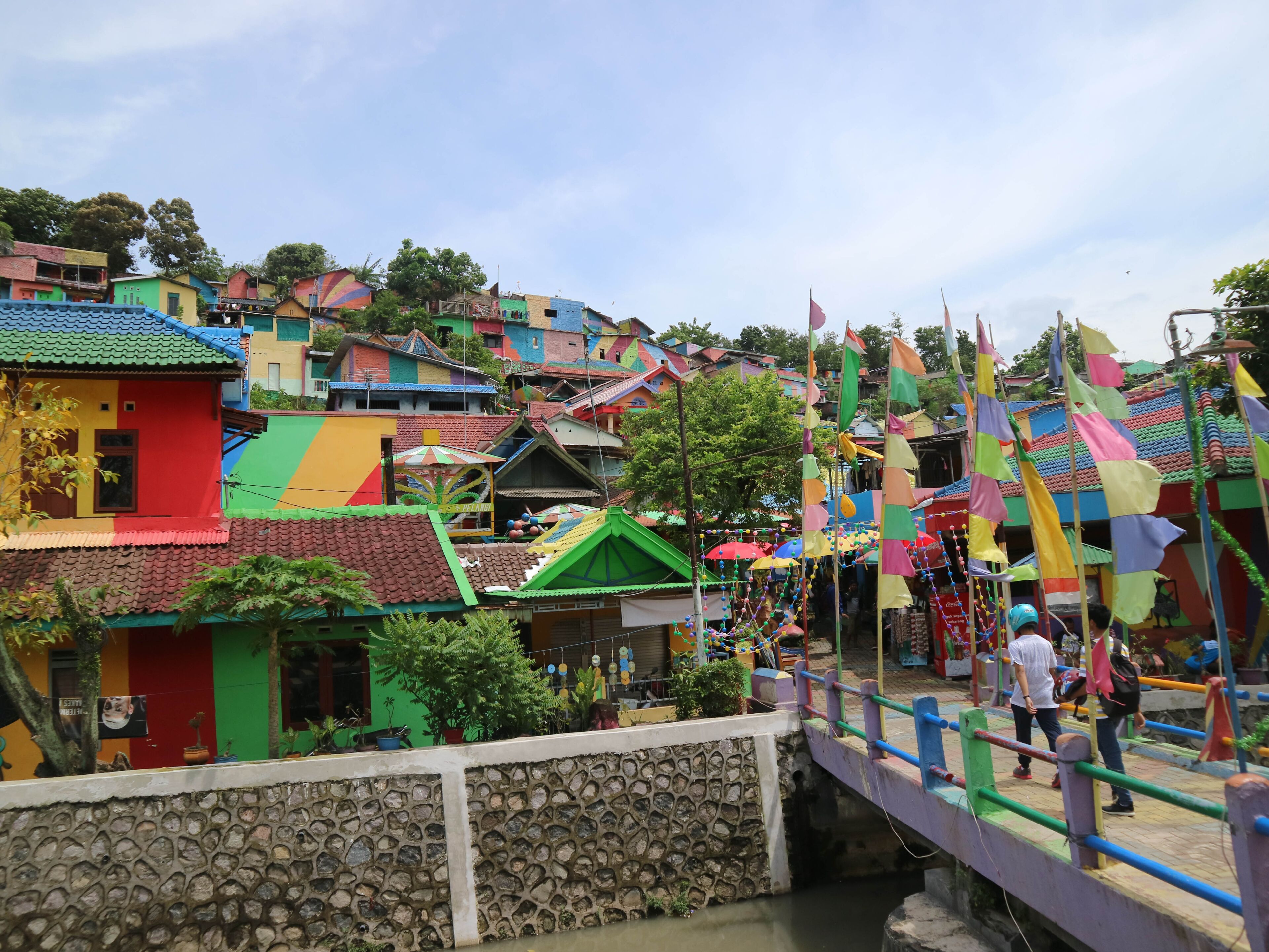 A colorful village with traditional houses, a stone bridge, and a river.