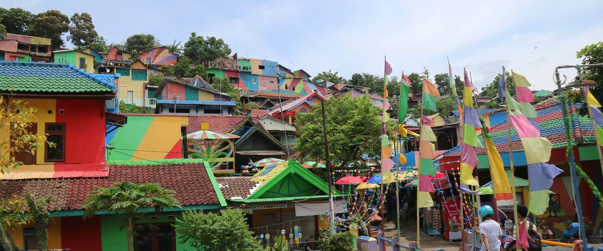 A colorful village with traditional houses, a stone bridge, and a river.