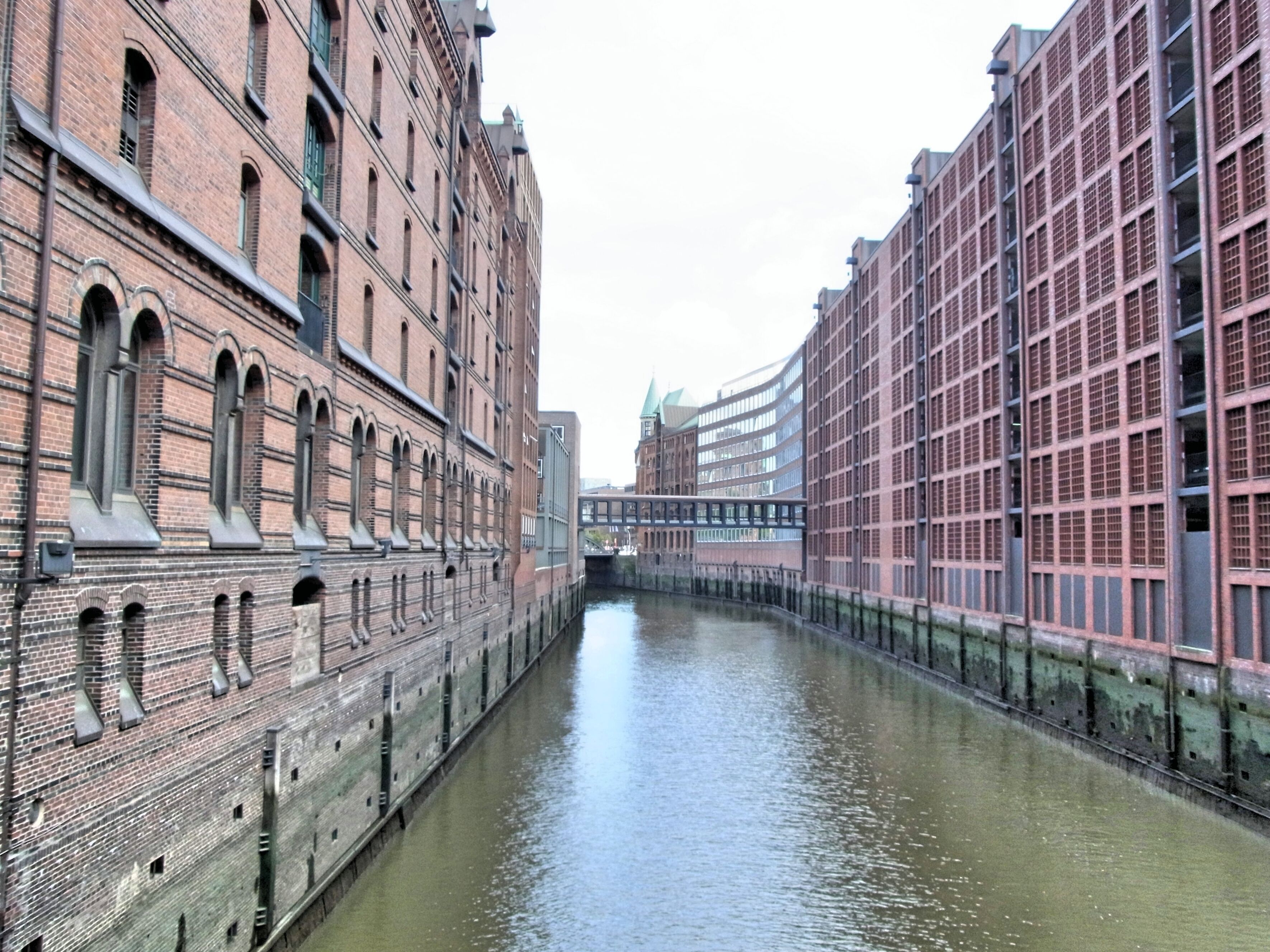 A canal flanked by historic brick buildings and a modern glass structure.