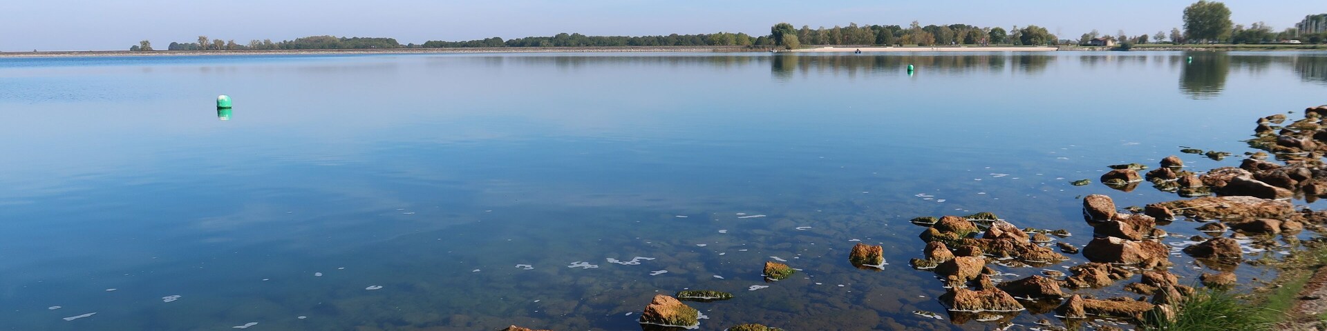 Paysage du lac du Der Chantecoq, en Champagne Ardenne, dans la région Grand Est, avec des pierres brunes dans l’eau bleue (France)