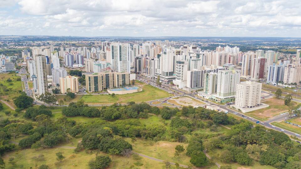 A cityscape with numerous high-rise buildings, green spaces, and a highway.