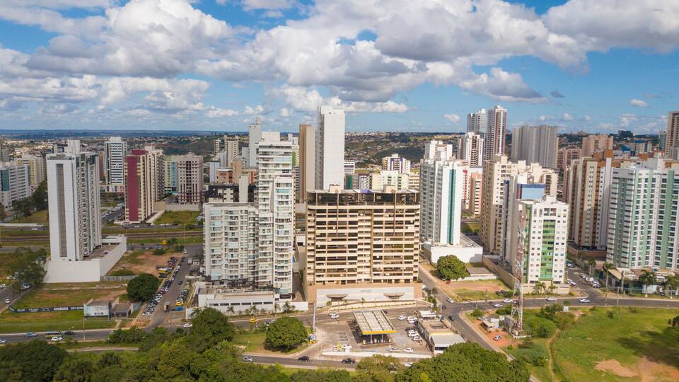 A cityscape with high-rise buildings, a parking lot, and a clear sky.
