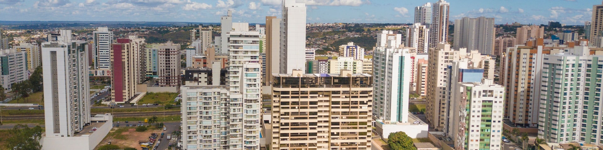 A cityscape with high-rise buildings, a parking lot, and a clear sky.