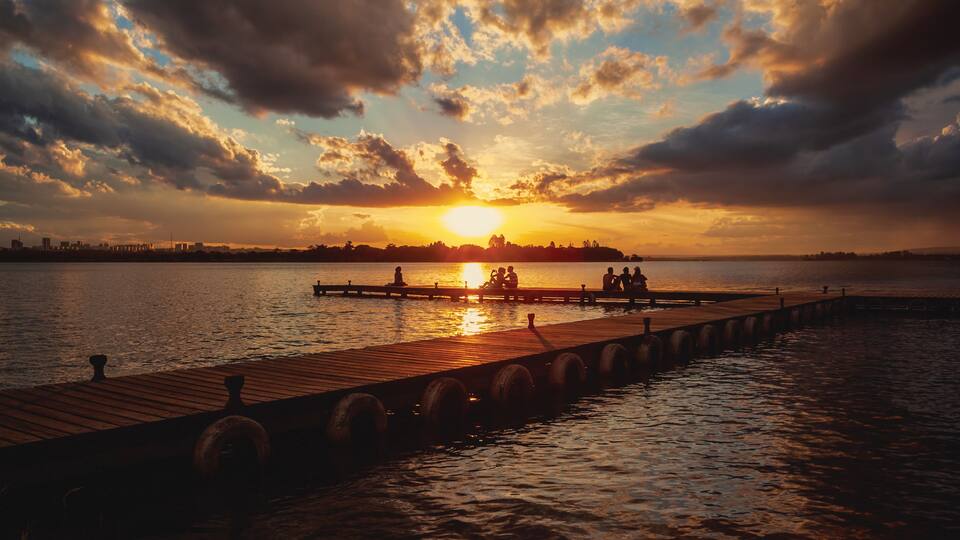 A sunset over a body of water with a wooden pier extending into the water.