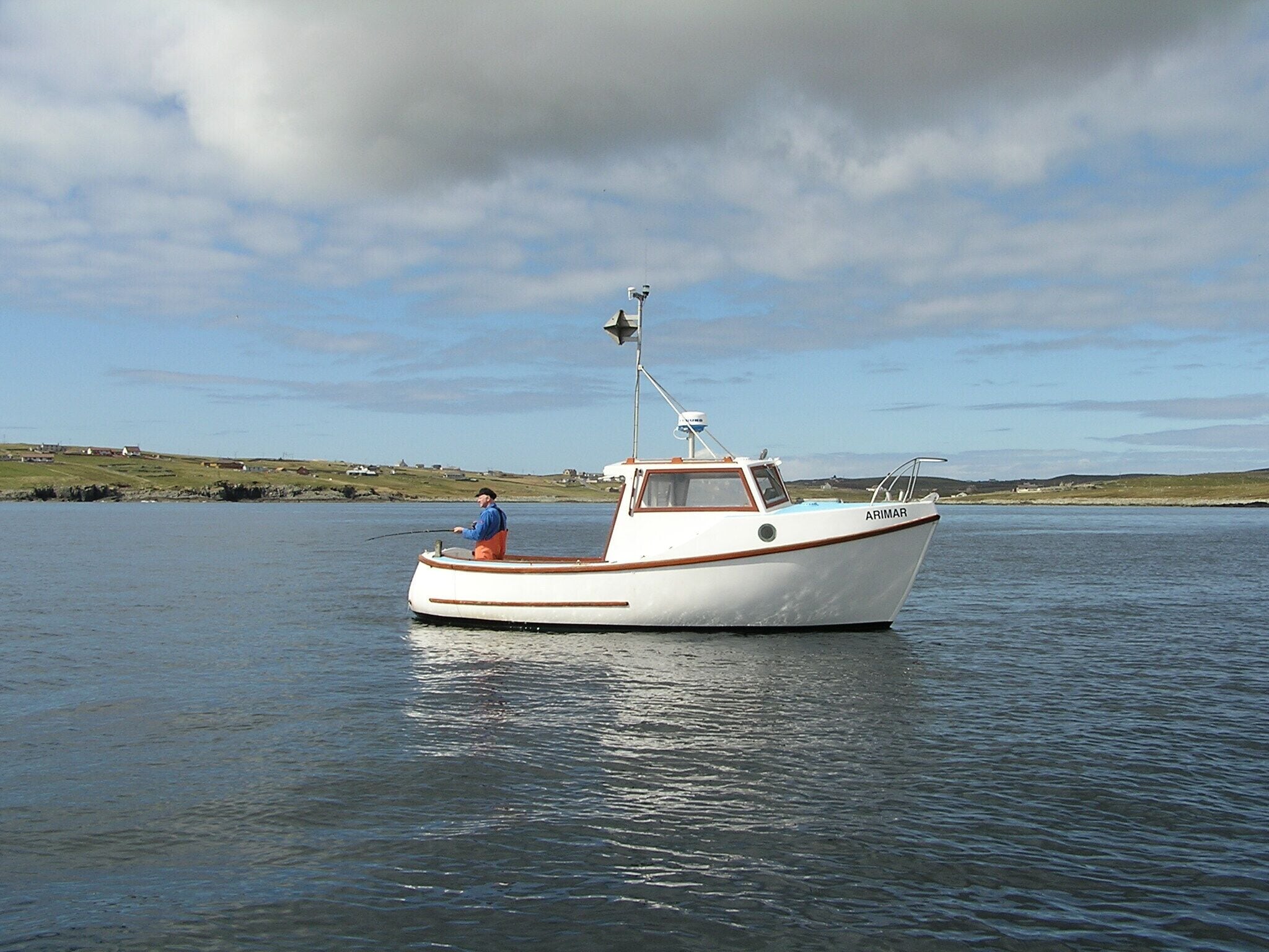 A small white boat named ARIMAR on calm water with a person fishing.