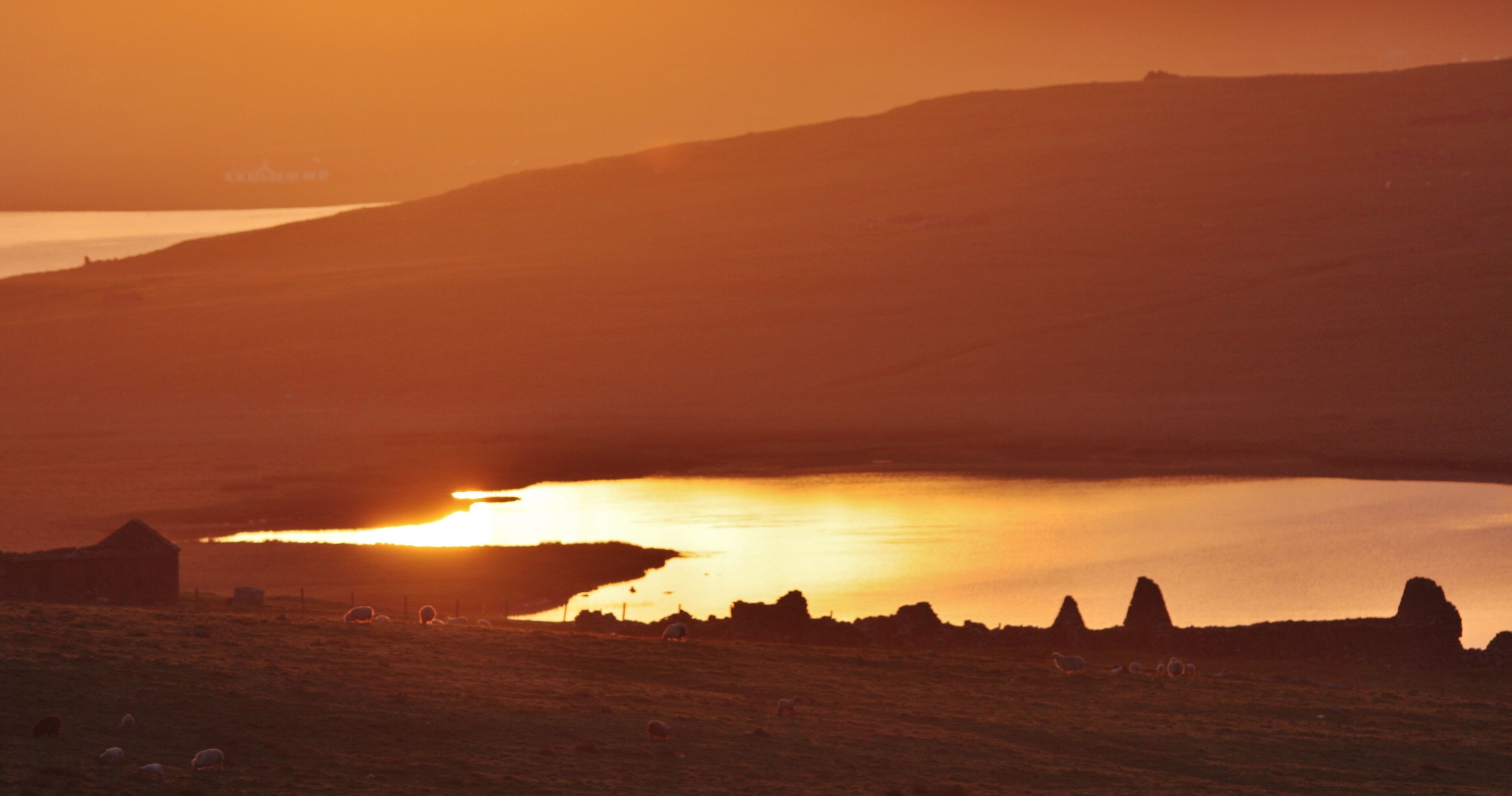 A sunset over a lake with hills in the background.