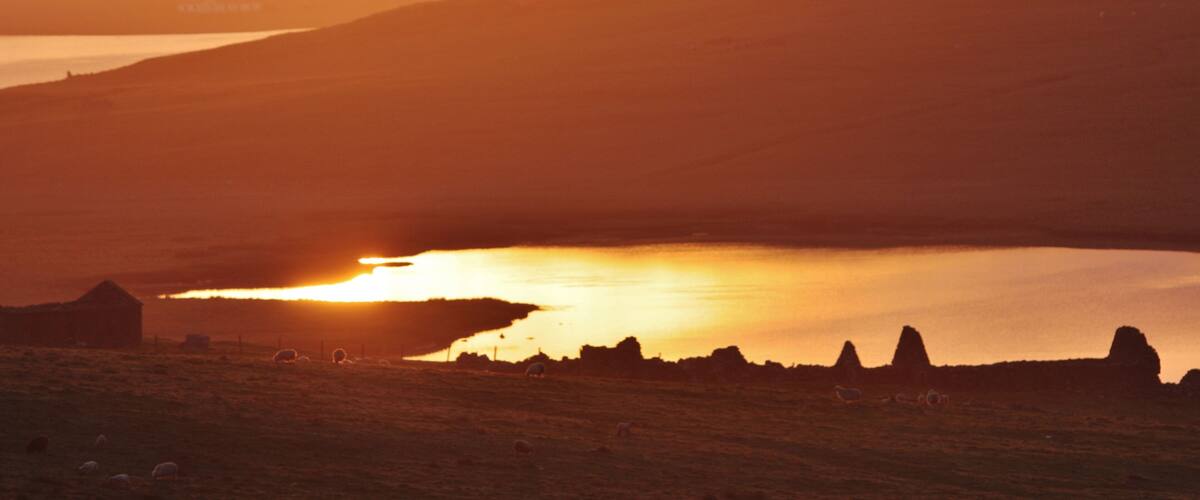 A sunset over a lake with hills in the background.