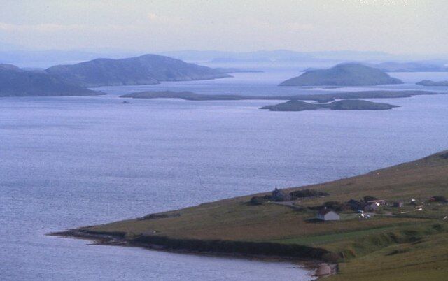 A coastal landscape with a small settlement by the water, surrounded by hills.
