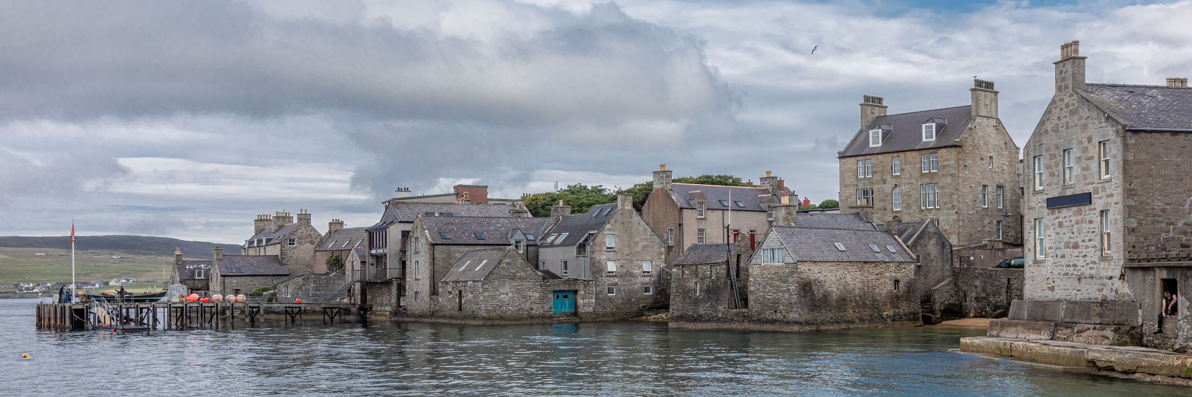 A coastal town with stone buildings and a pier.