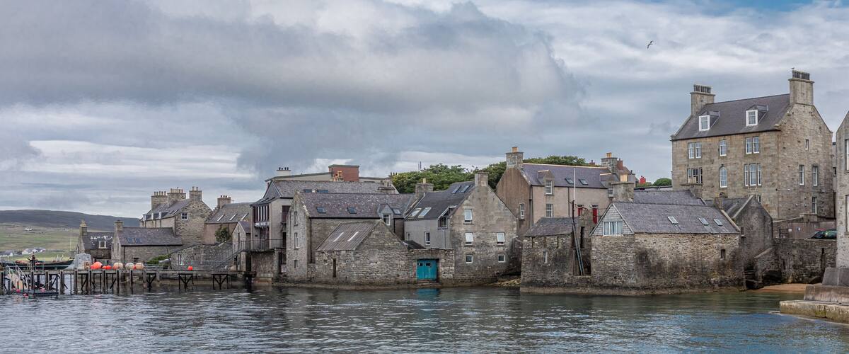 A coastal town with stone buildings and a pier.
