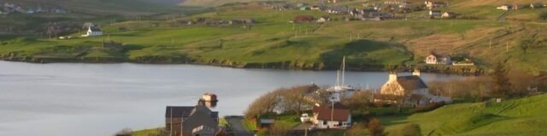 A coastal village with houses, a lighthouse, and a lake.