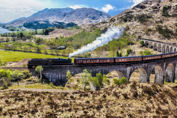 Glenfinnan Railway Viaduct in Scotland with the Jacobite steam train against sunset over lake