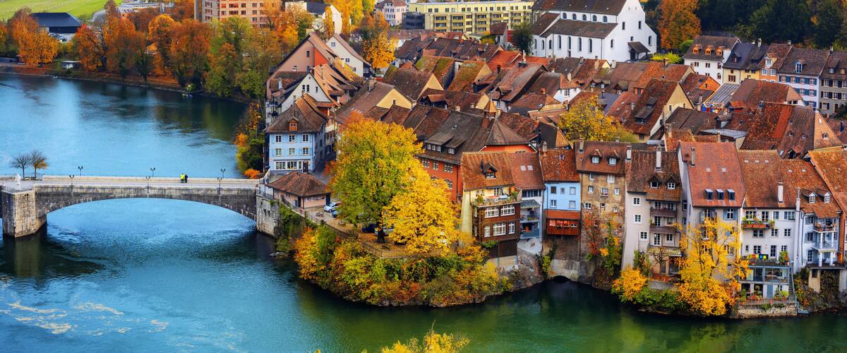 A river flowing through a town with historic buildings and a bridge.