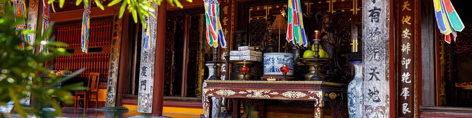 Um templo tradicional com decorações elaboradas, um altar central e bandeiras penduradas.
