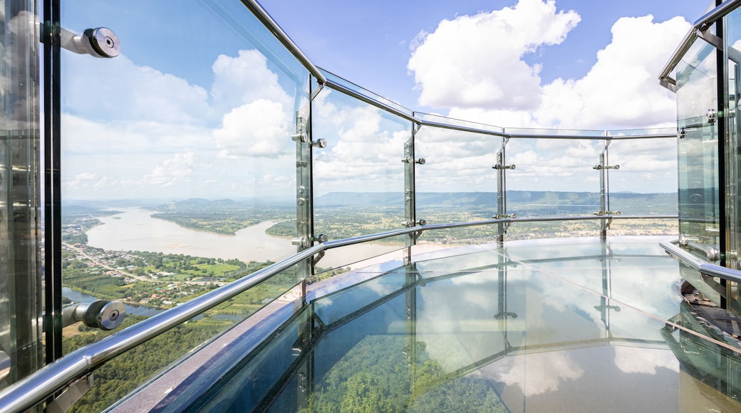 Una terraza de cristal con barandilla metálica que da a un río y paisaje.