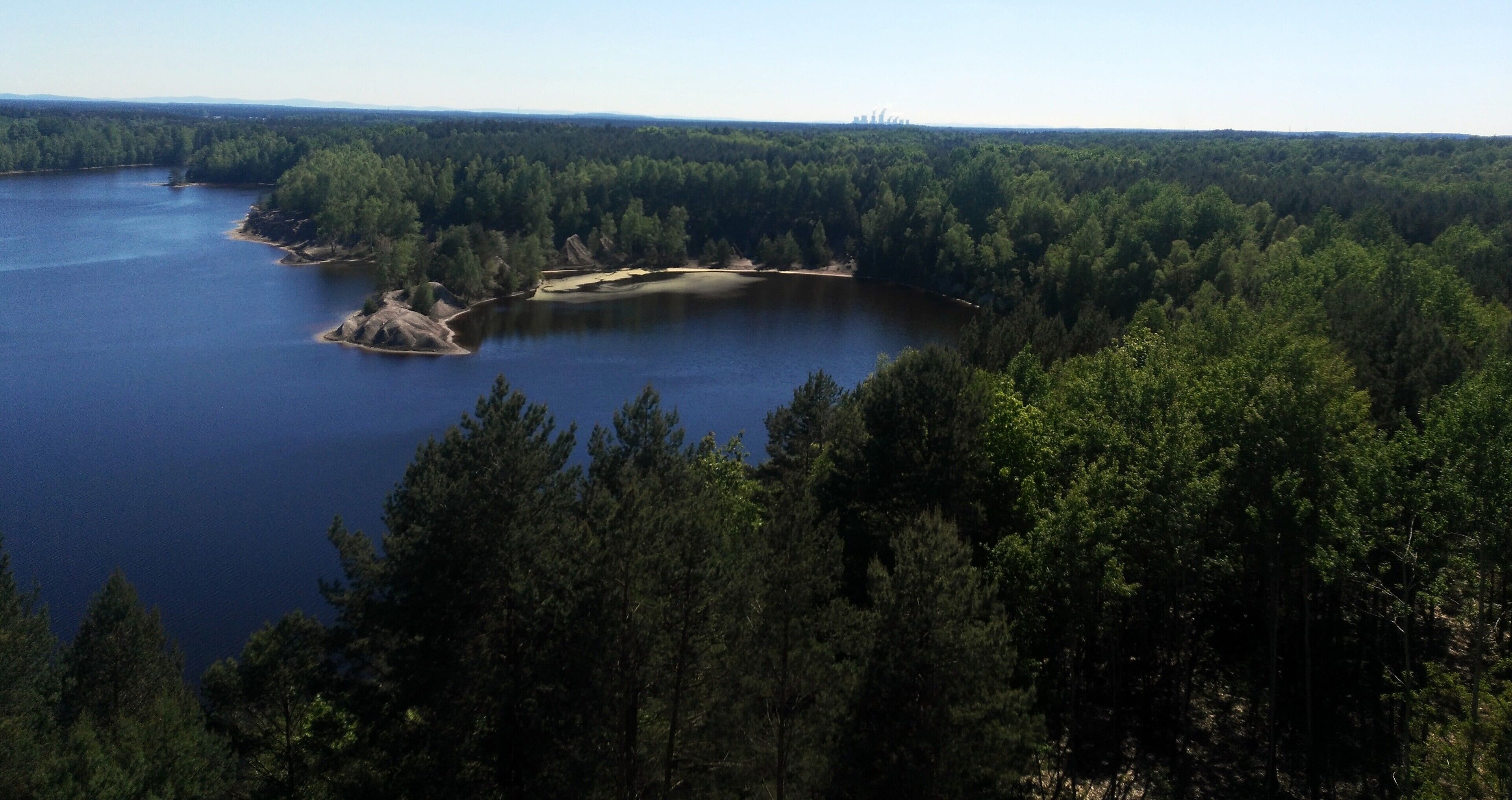 A lake surrounded by dense forest and rocky outcrops.