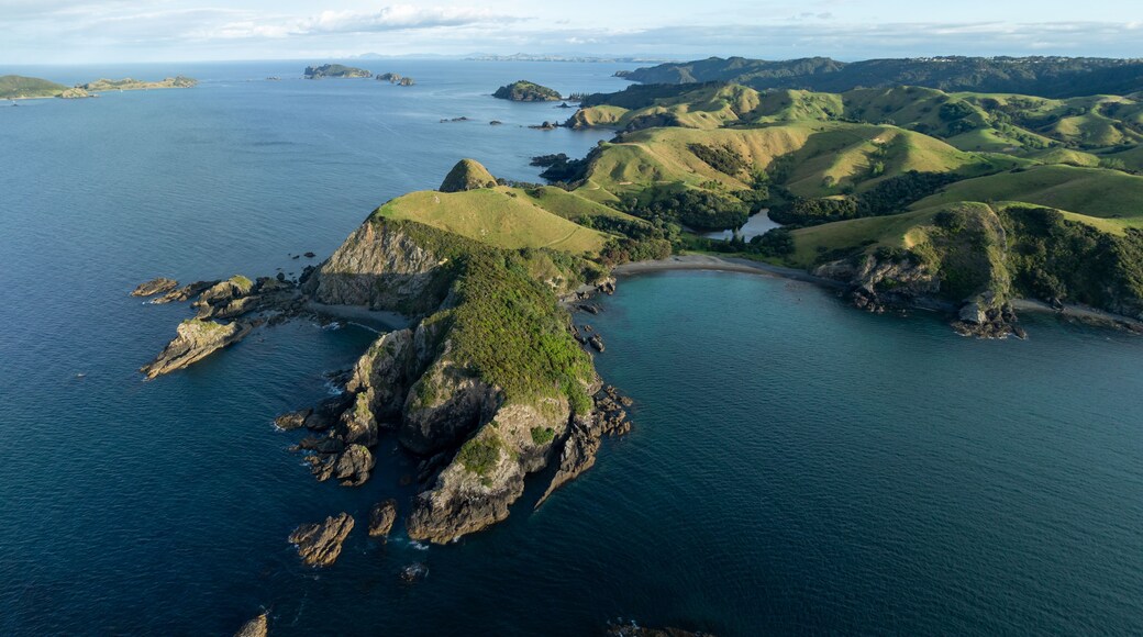 Un paisaje costero con acantilados escarpados, una bahía y colinas ondulantes.