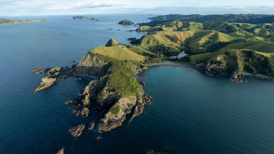 A coastal landscape with rugged cliffs, a bay, and rolling hills.