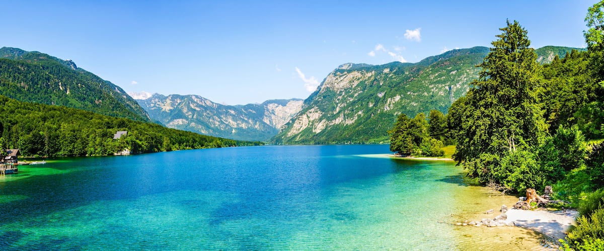 A clear lake surrounded by mountains and dense forests.