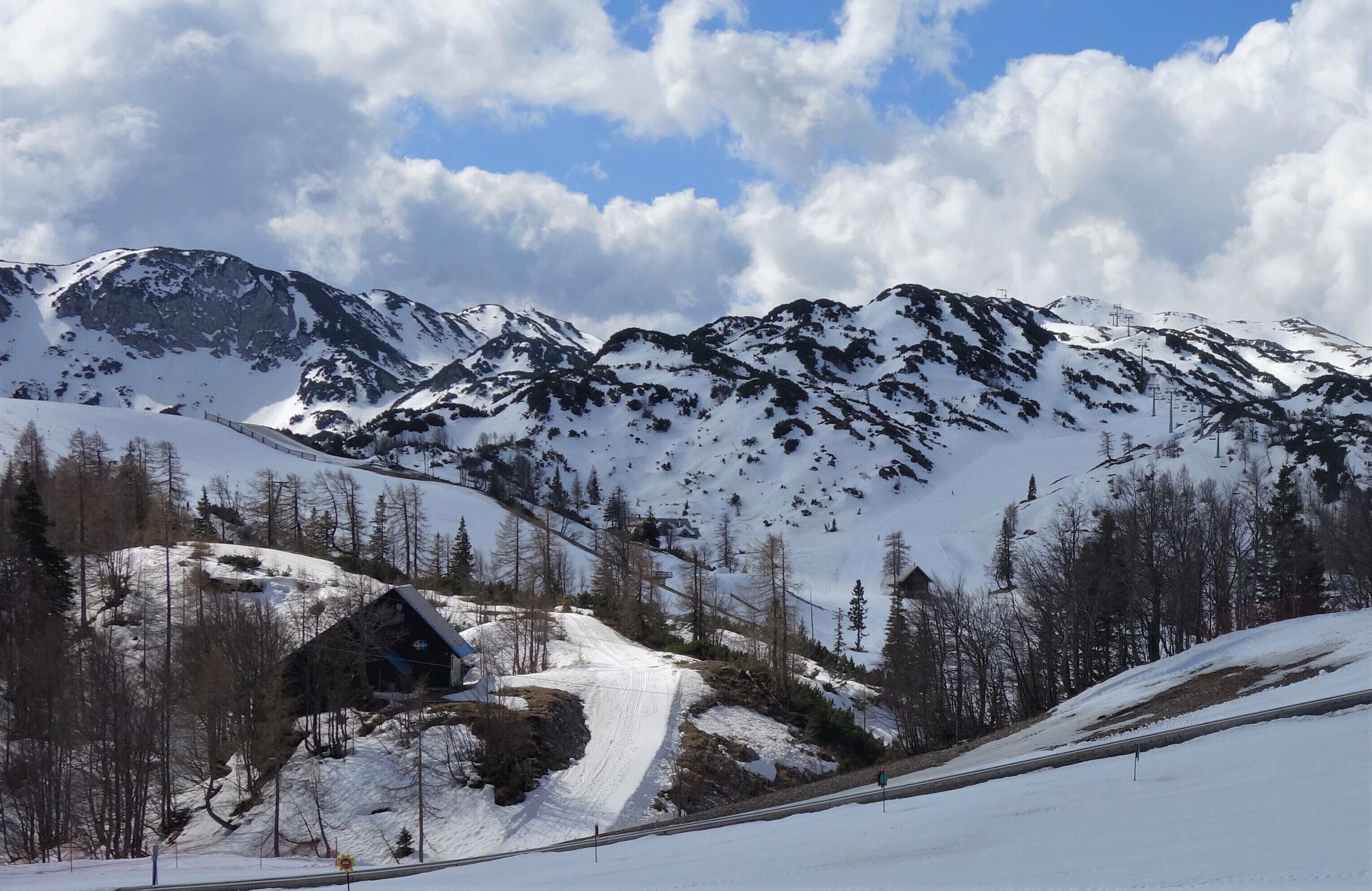Paisaje montañoso cubierto de nieve con un telesilla y una cabaña de madera.