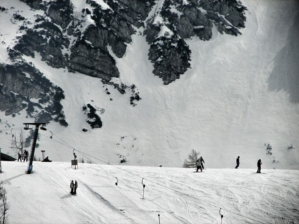 Pendiente nevada de una montaña con telesillas y esquiadores.