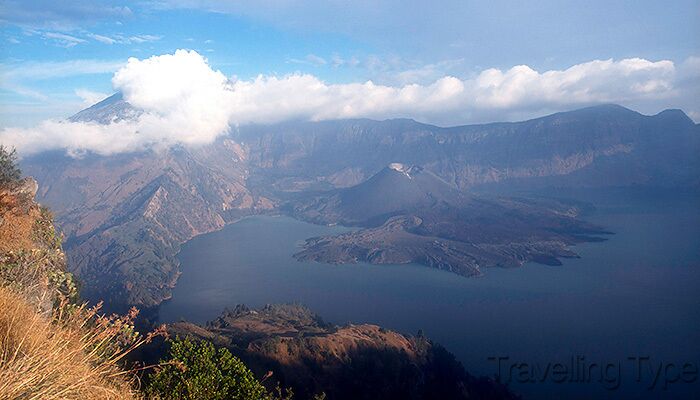 A mountainous landscape with a lake and a volcano.