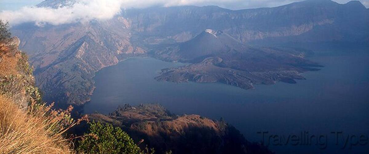 A mountainous landscape with a lake and a volcano.