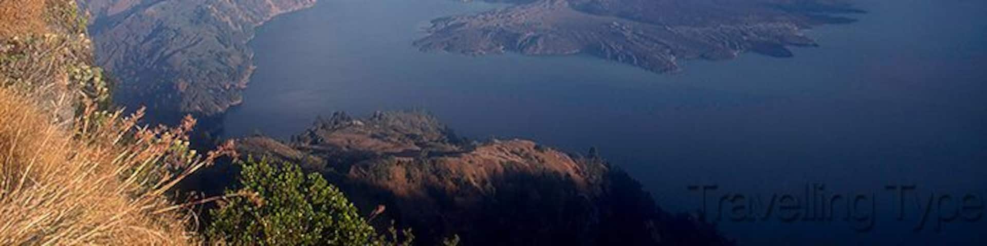 Un paisaje montañoso con un lago y un volcán.