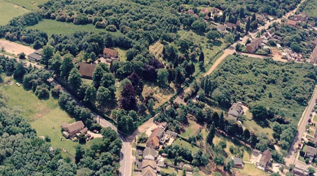 Aerial view of St Peters Church and Coombe Wood, Thundersley. St Peter's Church lies below-left of centre. The church spire is obscured by the trees. The road skirting the lower left is the Church Road. The road extending off this towards the upper right id Rhoda Road North. Much of this is unmade. The wood occupying the upper part is Coombe Wood. The lower right of the image shows the escarpment, seen from the other direction in 1635727.