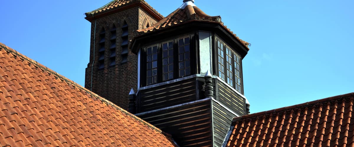A building with a tiled roof and a weather vane.