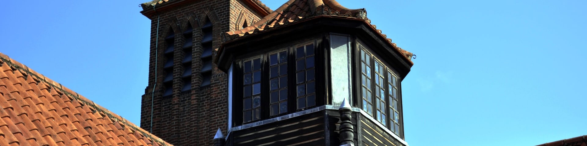 A building with a tiled roof and a weather vane.