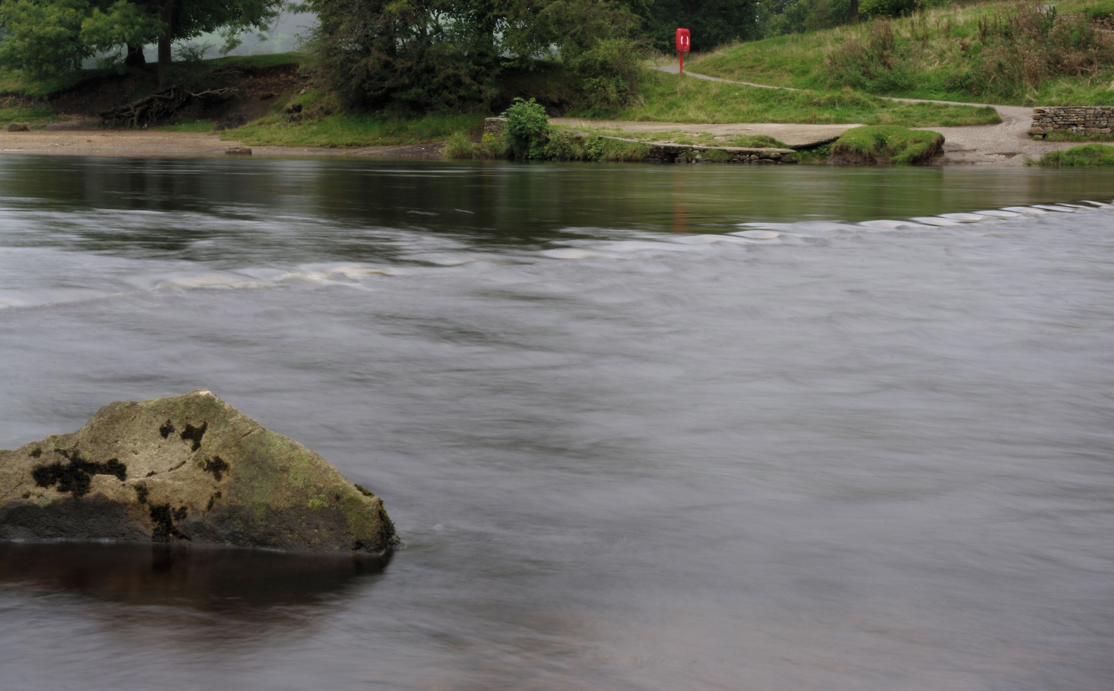 The River Wharfe rushing over a small waterfall at Bolton Abbey, Yorkshire.