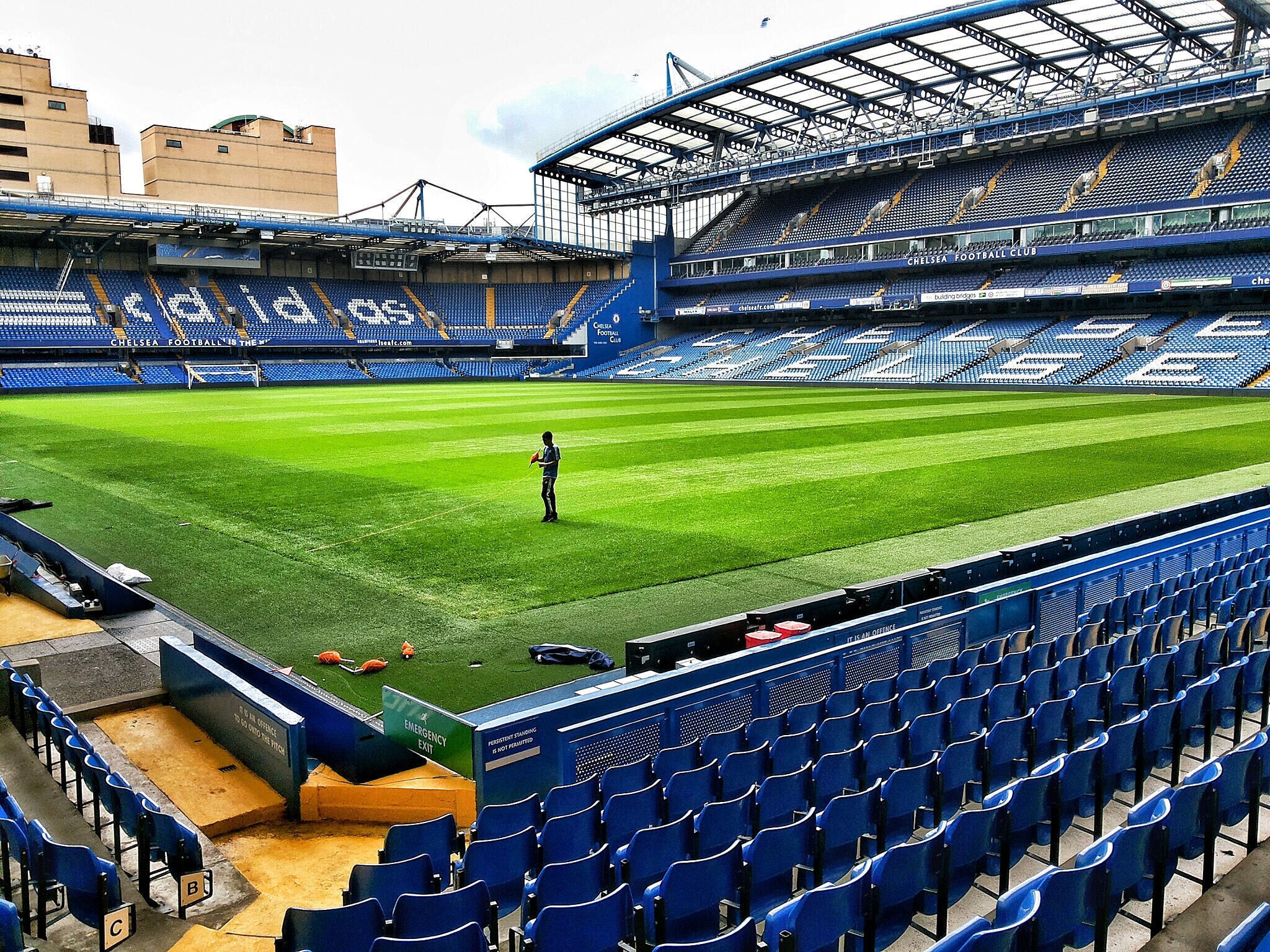 A large, empty stadium with blue seats and a green field.