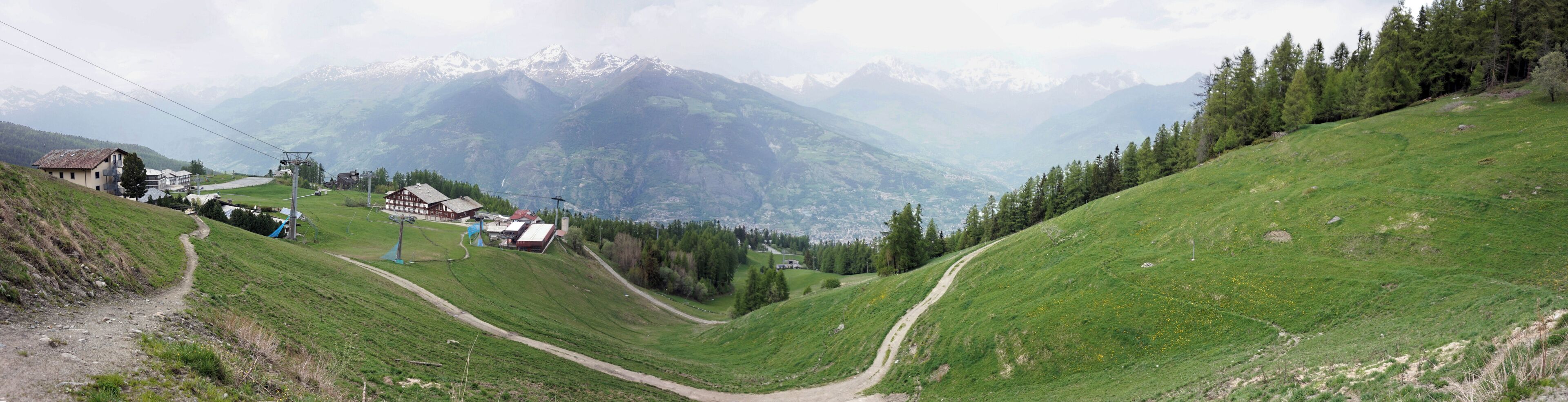A mountainous landscape with a ski lift, houses, and a winding path.