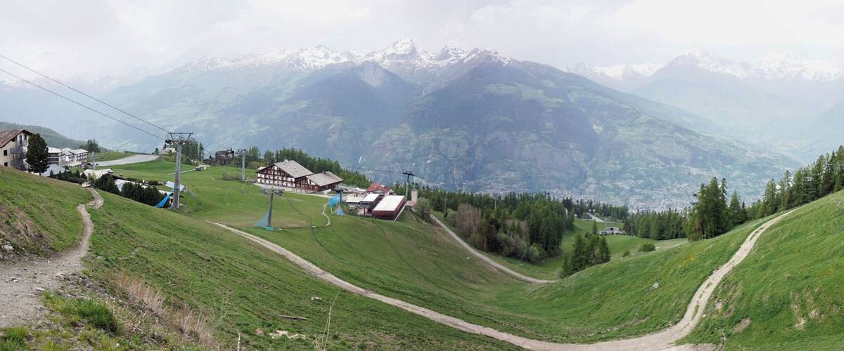 A mountainous landscape with a ski lift, houses, and a winding path.