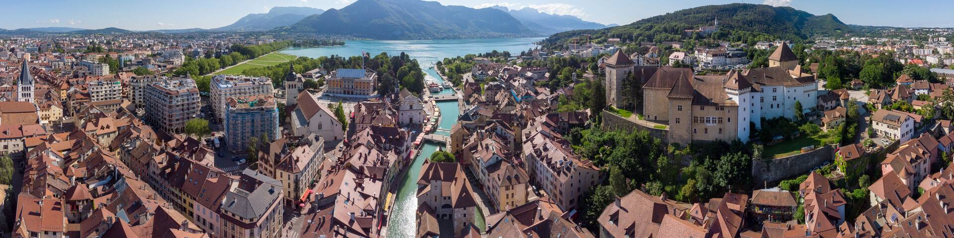 Annecy city center panoramic aerial view with the old town, castle, Thiou river and mountains surrounding the lake, beautiful summer vacation tourism destination in France, Europe