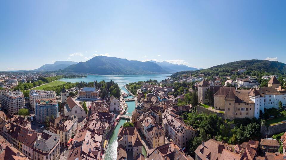 Annecy city center panoramic aerial view with the old town, castle, Thiou river and mountains surrounding the lake, beautiful summer vacation tourism destination in France, Europe