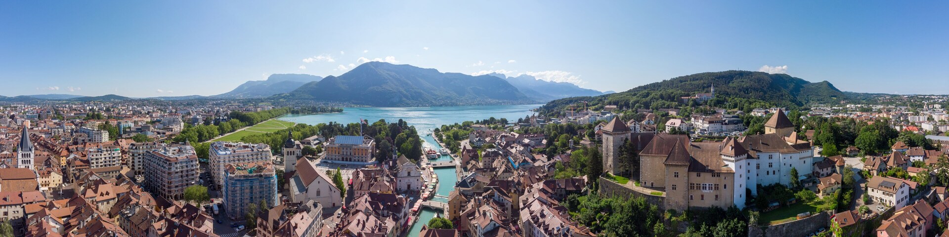 Annecy city center panoramic aerial view with the old town, castle, Thiou river and mountains surrounding the lake, beautiful summer vacation tourism destination in France, Europe