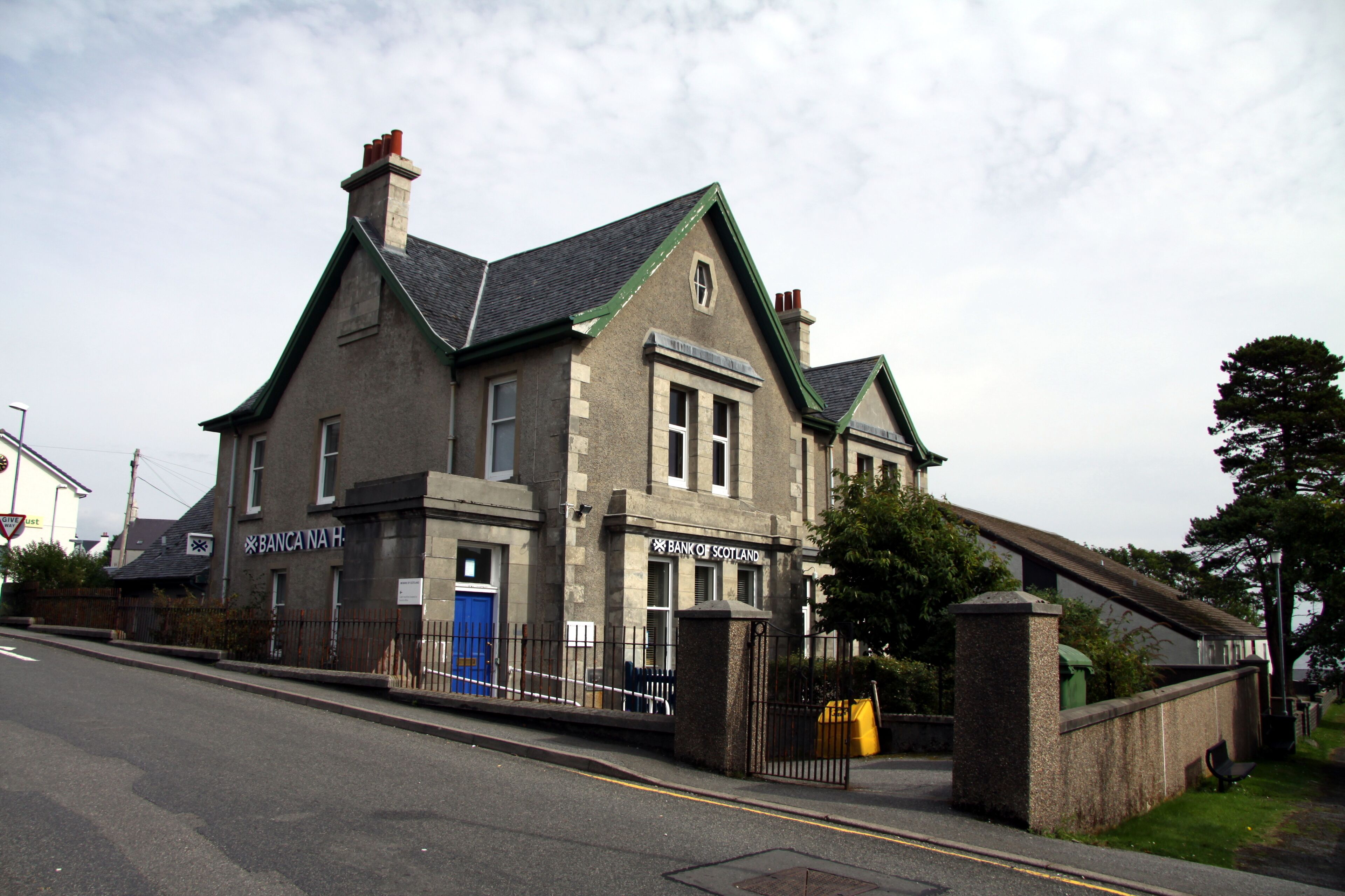 A two-story building with a green roof and a sign that reads "Bank of Scotland."