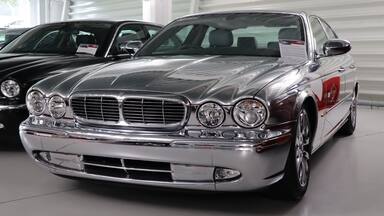 A classic car with a chrome grille and round headlights in a showroom.