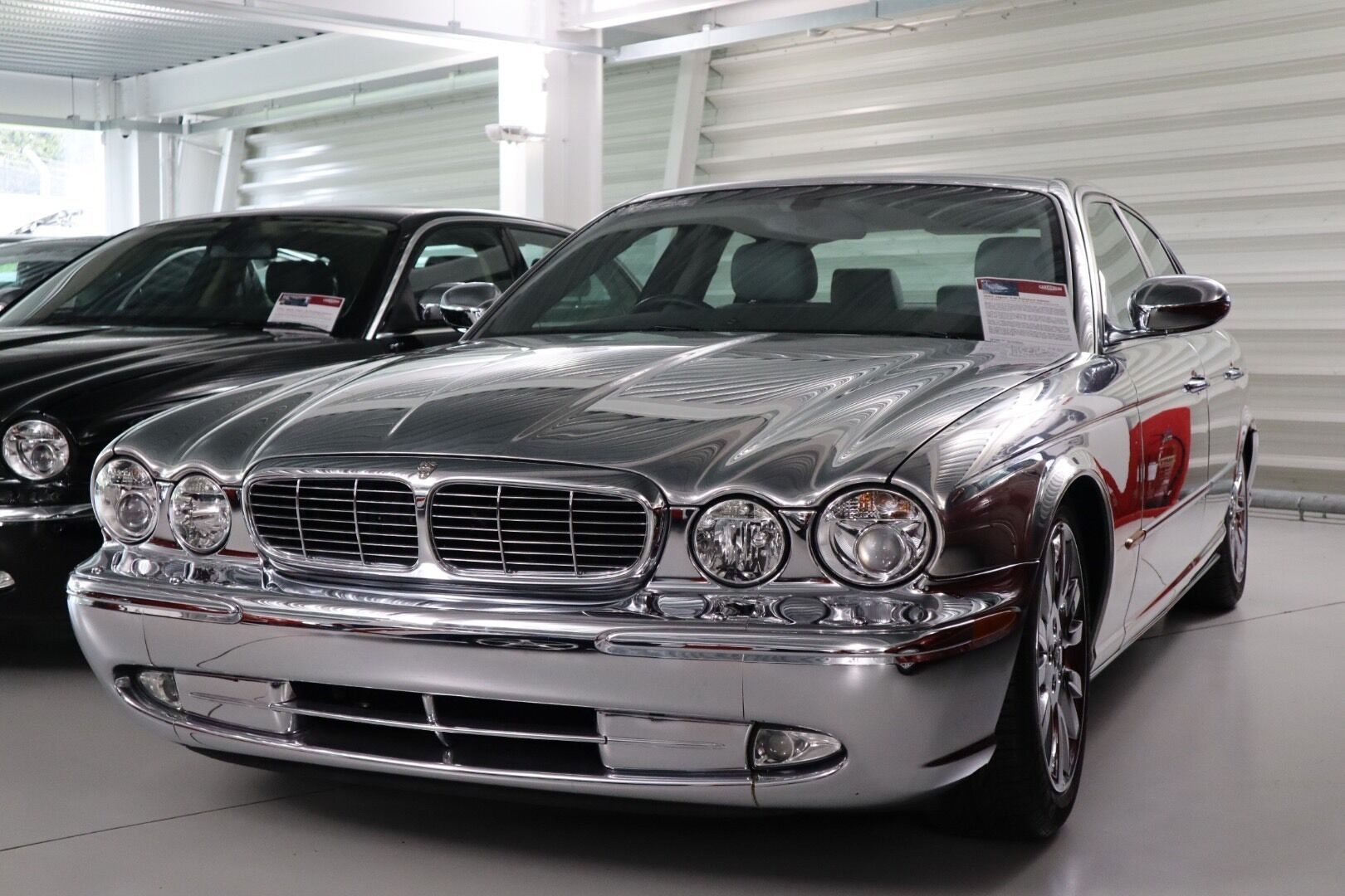 A classic car with a chrome grille and round headlights in a showroom.