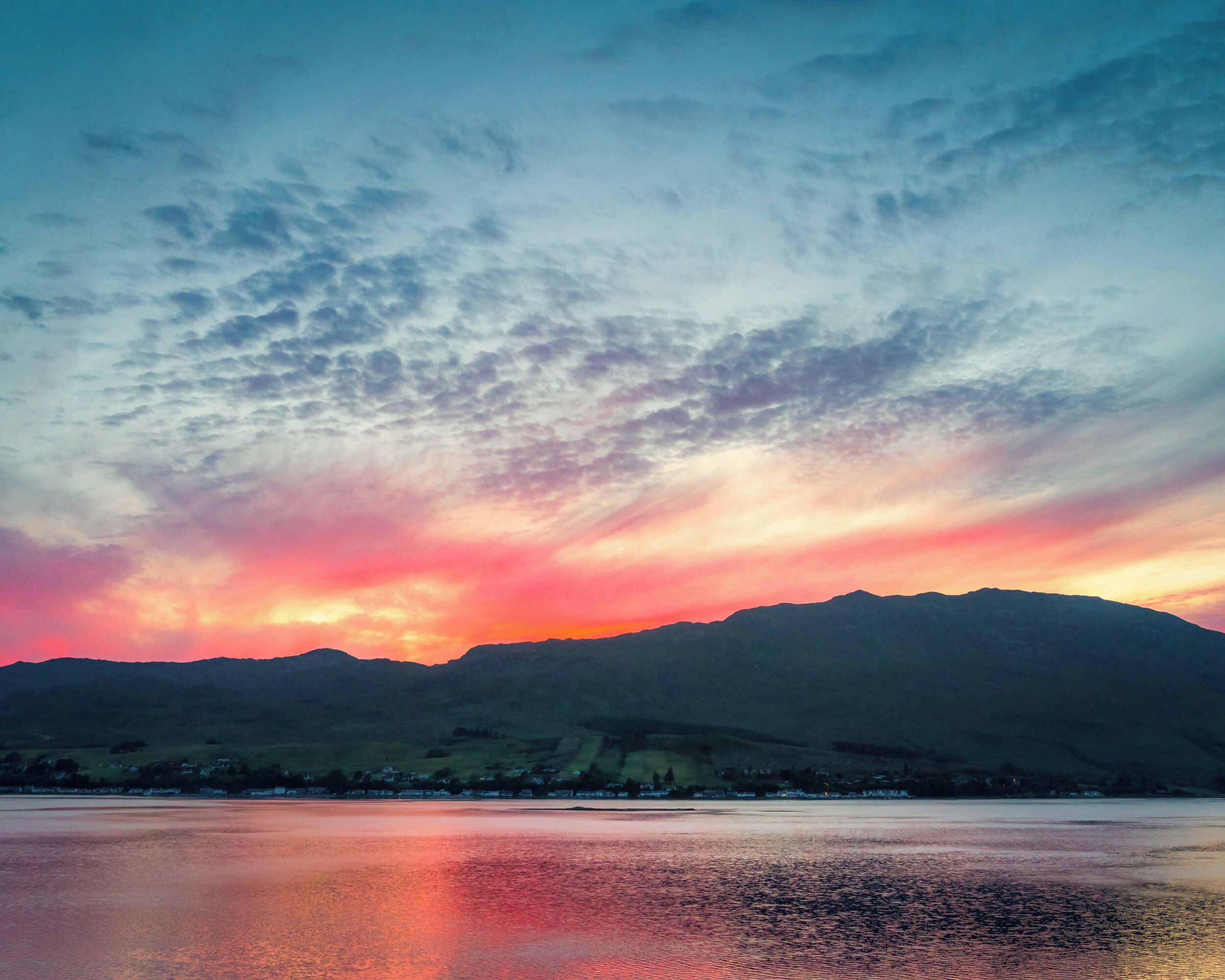 A sunset over a lake with mountains in the background.