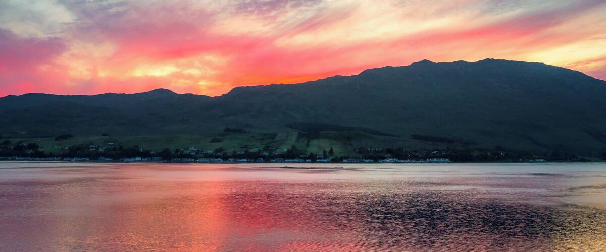 A sunset over a lake with mountains in the background.